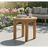 Teakea ronde houten tuintafel van duurzaam teakhout op een modern betegeld terras, gedecoreerd met boeken en een kop koffie in de lentezon.