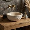 Sfeervol toilet met ruime natuurstenen waskom op eikenhouten plank.
