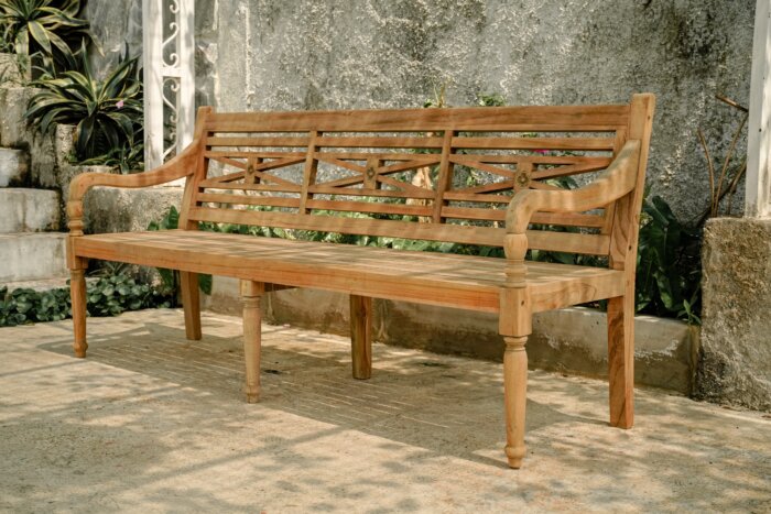 Klassieke teakhouten stationsbank, 180 cm breed. De bank heeft een traditioneel design met een rechte rugleuning en een stevige, vlakke zitting. Het hout heeft een natuurlijke, warme teakkleur en is fijn afgewerkt, wat de elegante uitstraling benadrukt. D