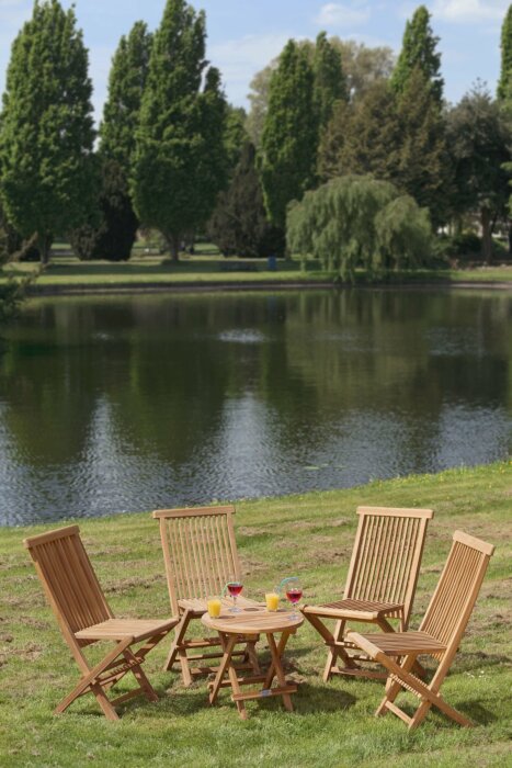 Gezellige teakhouten tuinset voor vier personen, bestaande uit vier vouwstoelen en een ruime, rechthoekige klaptafel, opgesteld op een terras in de tuin.